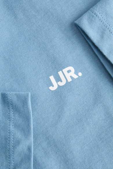 Blauw T-shirt met korte mouwen van JJREBEL, close-up met stiksels en het logo op de voorkant.
