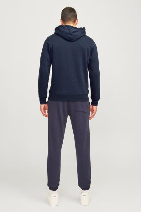 Blauwe sweater met kap van JJREBEL, gecombineerd met een joggingbroek en witte sneakers.