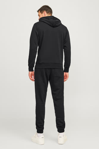 Zwarte joggingbroek van JJREBEL, gezien van achteren, met witte sneakers.