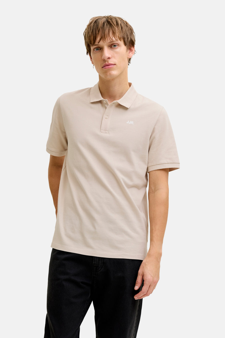 Beige polo van JJREBEL, met korte mouwen en gedragen met een zwarte jeans.
