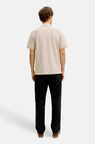 Beige polo van JJREBEL, gezien van achteren, gecombineerd met zwarte jeans en bruine schoenen.
