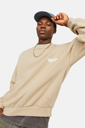 Gilet beige d'ORIGINALS BY JACK & JONES, avec une chaîne argentée et un chapeau bleu.