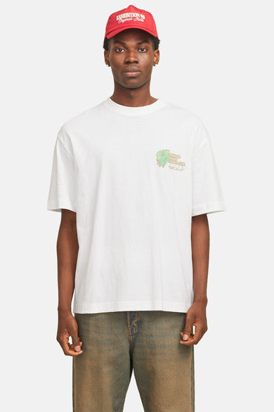 Wit T-shirt met korte mouwen van ORIGINALS BY JACK & JONES, met een logo op de borst en gedragen met een rode pet en jeans.
