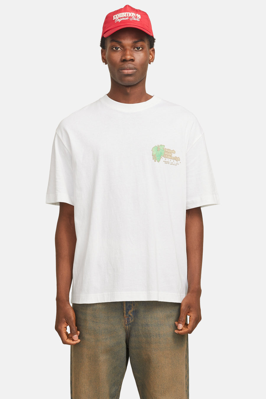 Wit T-shirt met korte mouwen van ORIGINALS BY JACK & JONES, met een logo op de borst en gedragen met een rode pet en jeans.
