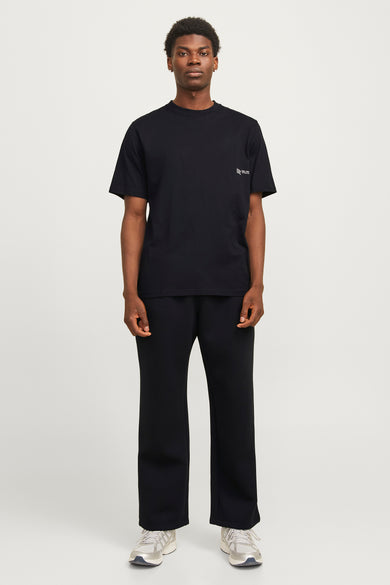 Zwart T-shirt met korte mouwen van CORE BY JACK & JONES, gecombineerd met een zwarte broek en witte sneakers.