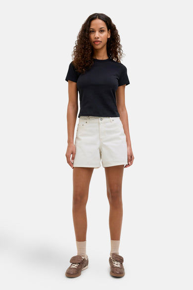 Witte short van JJXX, gecombineerd met een zwart T-shirt en bruine sneakers.