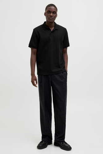 Zwarte polo met korte mouwen van CORE BY JACK & JONES, met een subtiele textuur en gedragen met een pantalon en leren schoenen.
