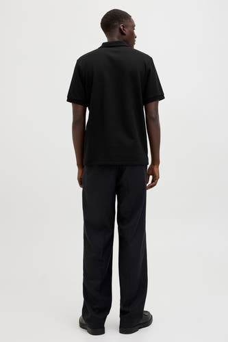 Zwarte polo met korte mouwen van CORE BY JACK & JONES, gezien van achteren, met lange zwarte broek en zwarte schoenen.
