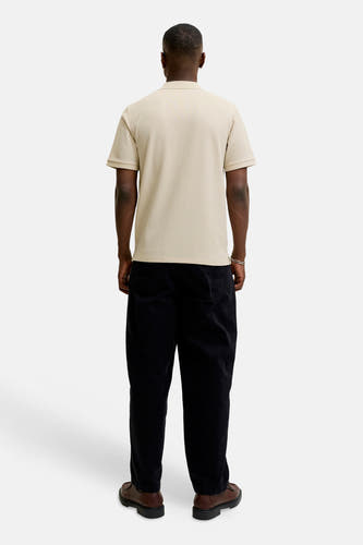 Beige polo met korte mouwen van CORE BY JACK & JONES met wafelstructuur, van achteren gezien op een man met zwarte broek en bruine schoenen.