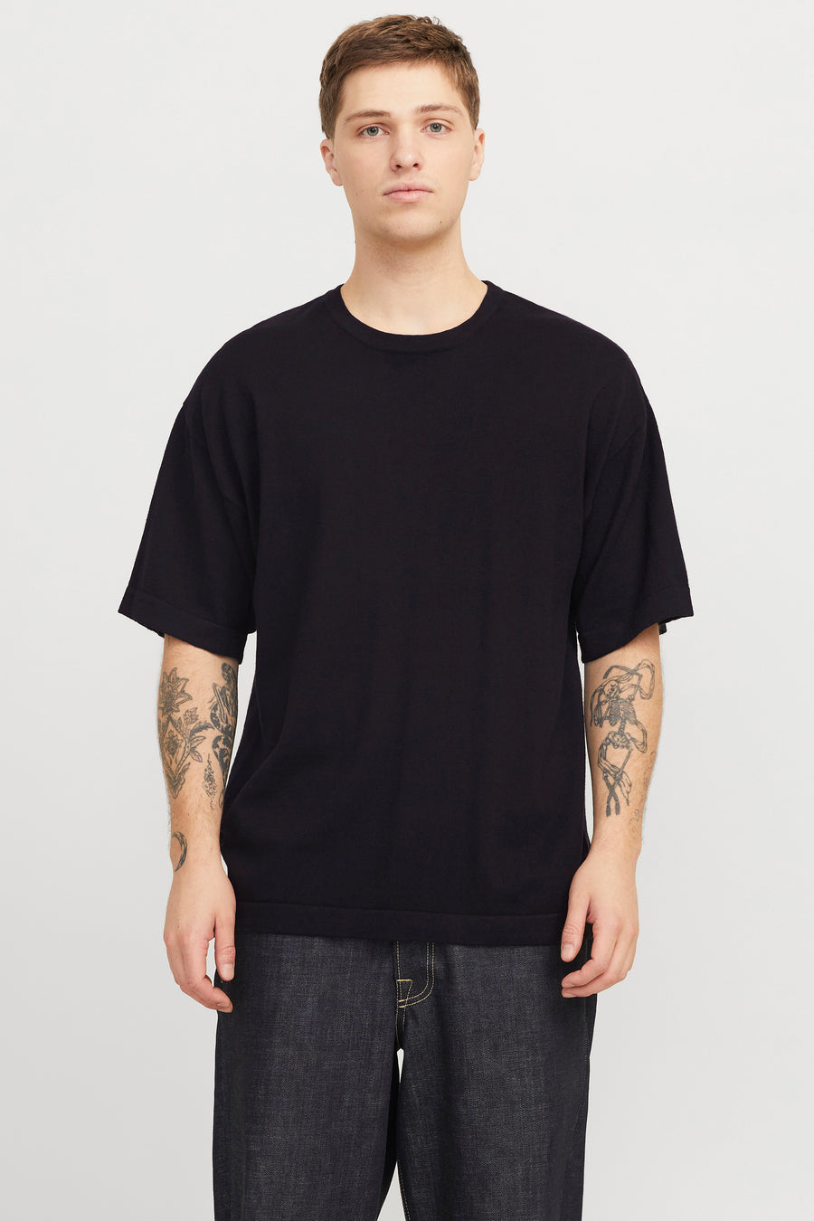 Zwart T-shirt met korte mouwen van PREMIUM by JACK & JONES, met tatoeages op beide armen, gecombineerd met een donkere jeans.
