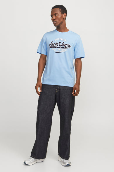 Blauw T-shirt met korte mouwen van JACK & JONES, met tekstprint op de voorkant, gecombineerd met donkere jeans en zilverkleurige sneakers.
