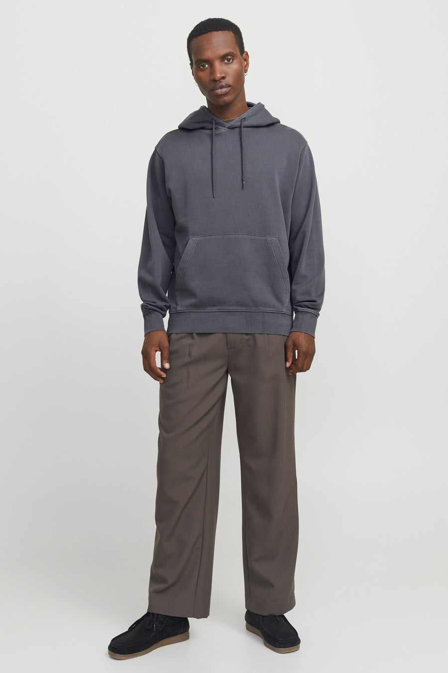 Grijze hoodie van CORE BY JACK & JONES met trekkoorden en kangoeroezak, gedragen door een model met bruine wijde broek en zwarte suède schoenen.