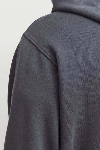 Grijze hoodie van CORE BY JACK & JONES met zichtbare ribtextuur en schoudernaad in close-up.