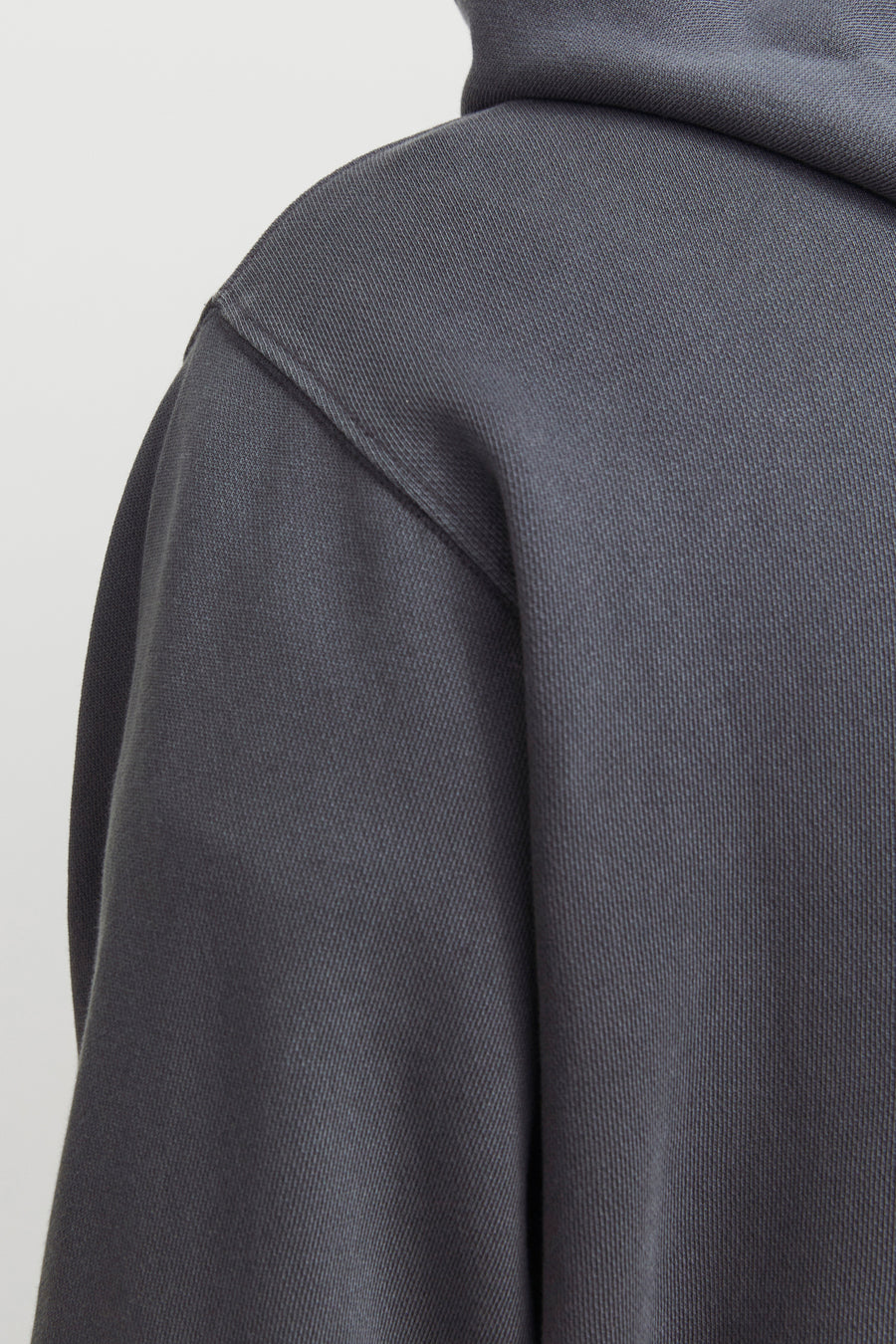 Grijze hoodie van CORE BY JACK & JONES met zichtbare ribtextuur en schoudernaad in close-up.