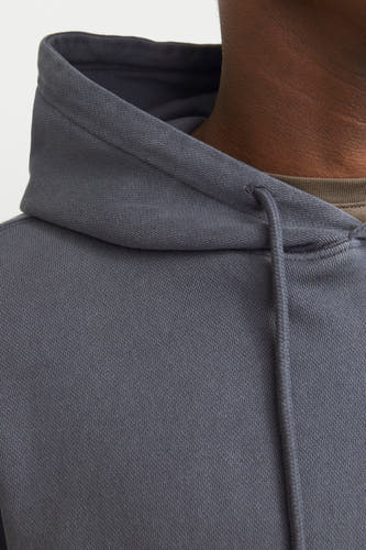 Close-up van een grijze hoodie van CORE BY JACK & JONES met fijne ribstructuur, trekkoorden en een olijfgroen T-shirt.