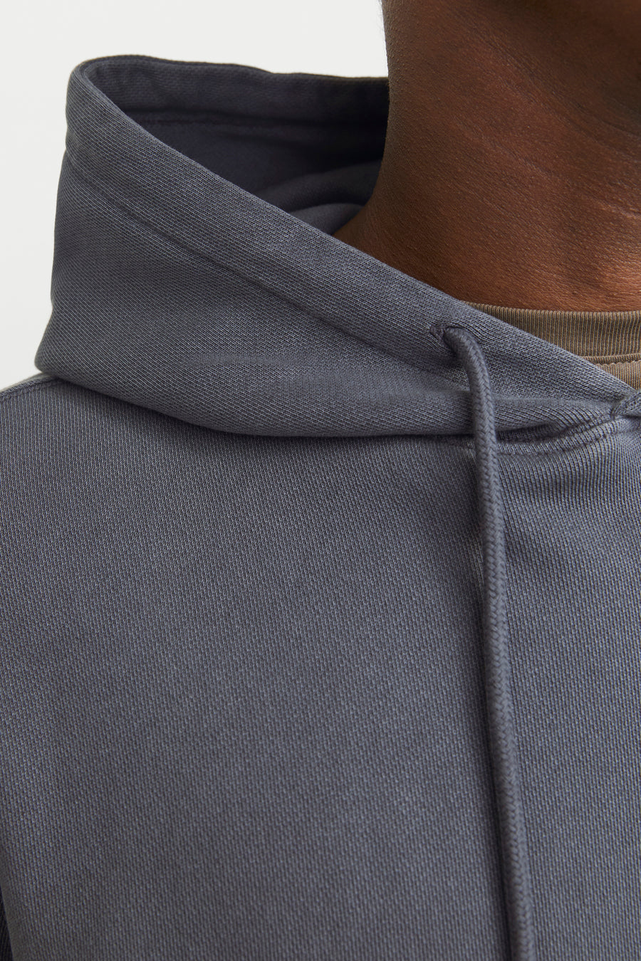 Close-up van een grijze hoodie van CORE BY JACK & JONES met fijne ribstructuur, trekkoorden en een olijfgroen T-shirt.