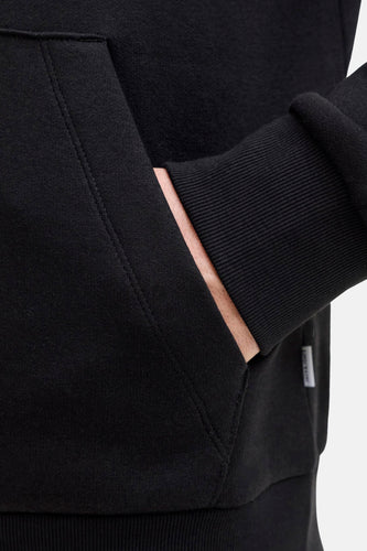 Zwarte hoodie met hand in zak.