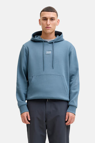 Pull-over bleu avec capuche de CORE by JACK & JONES, à longues manches et poche kangourou, associé à des pantalons foncés et des baskets blanches.