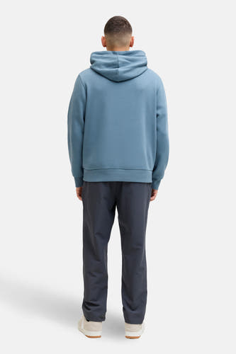 Pull-over bleu avec capuche de CORE BY JACK & JONES, vu par derrière, avec un pantalon gris foncé et des baskets crème.