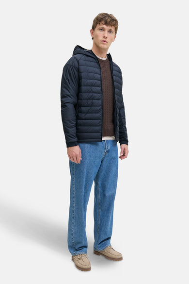 Manteau court bleu de CORE BY JACK & JONES, avec capuche, associé à une chemise brune et des jeans bleus.