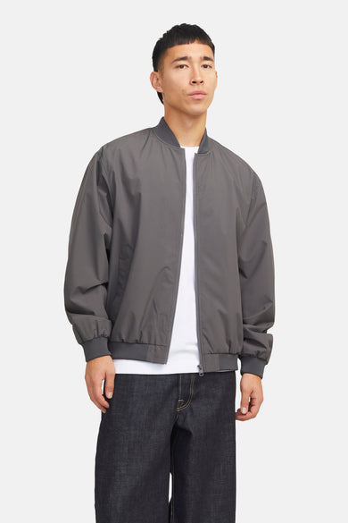 Korte grijze jas van PREMIUM by JACK & JONES, met lange mouwen en een witte T-shirt en donkere broek.
