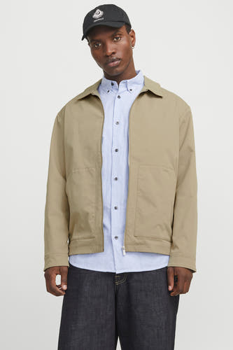 Manteau court beige d'ORIGINALS BY JACK & JONES, porté sur un chemisier rayé bleu et une casquette noire.