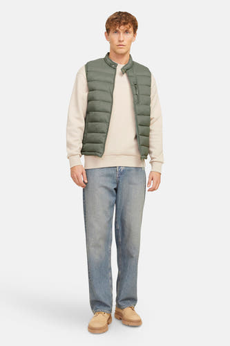 Bodywarmer in kaki, van PREMIUM BLUE by JACK & JONES, gedragen over een beige sweater en blauwe jeans.

