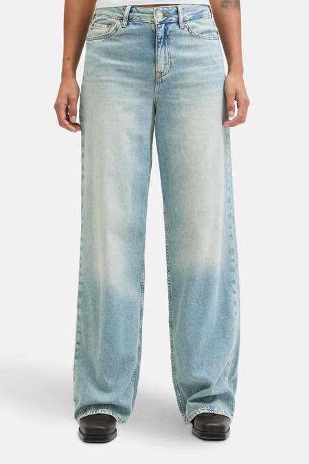 Lichtblauwe denim wijde pijpen jeans van JJXX, met vintage wassing en zwarte schoenen.

