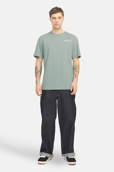 Groen T-shirt met korte mouwen van Originals by Jack & Jones, met een klein logo op de borst, gecombineerd met donkere jeans en sneakers.
