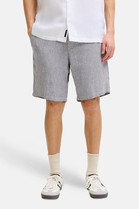 Grijze gemêleerde short van JACK & JONES JEANS INTELLIGENCE, gedragen door een man met witte sneakers en een wit overhemd.