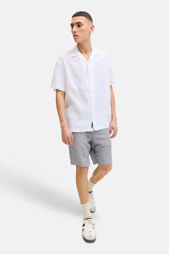 Blauwe short van JACK & JONES JEANS INTELLIGENCE met een geweven textuur, gedragen door een man in een wit overhemd en sneakers.