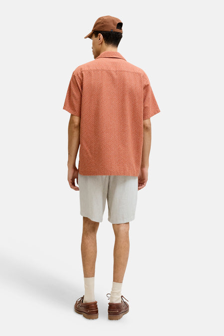 Beige short van JACK & JONES JEANS INTELLIGENCE, van achteren gezien op een man met een oranje overhemd met patroon en bruine bootschoenen.