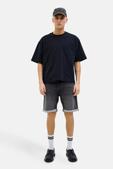 Jean noir court de Jack & Jones Jeans Intelligence, avec des poches rabattues, porté avec des chaussettes blanches et des chaussures noires.