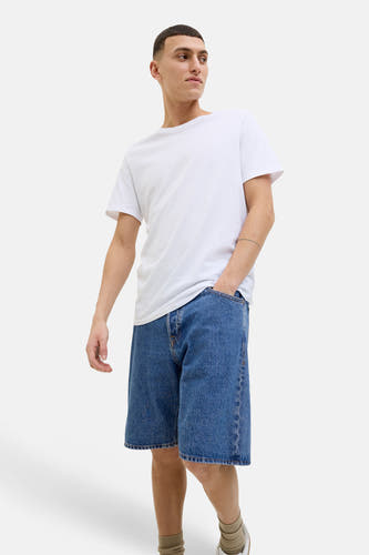 Short en jean de couleur bleu moyen de JACK & JONES JEANS INTELLIGENCE, porté par un homme avec un t-shirt blanc, la main dans la poche.