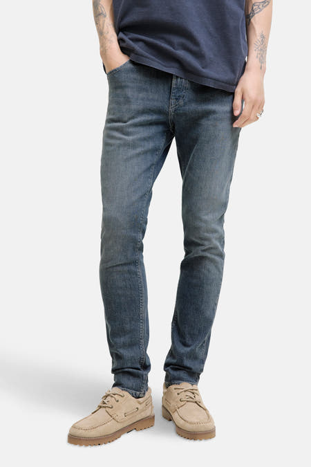 Slim fit jeans van JACK & JONES JEANS INTELLIGENCE, in middengrijs denim, met lichtbruine schoenen.