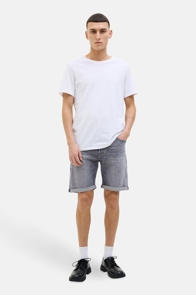 Grijze jeansshort van JACK & JONES JEANS INTELLIGENCE, met opgerolde zoom, gecombineerd met een wit T-shirt en zwarte schoenen.
