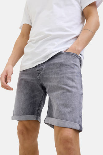 Grijs denim jeansshort van JACK & JONES JEANS INTELLIGENCE, met omgeslagen pijpen en een model met een hand in de zak.
