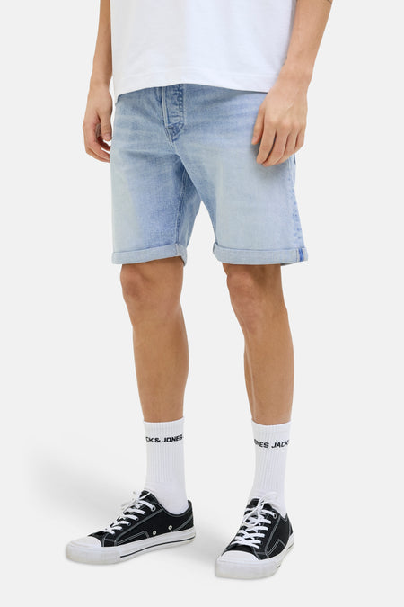 Lichtblauwe denim jeansshort van JACK & JONES JEANS INTELLIGENCE, met omgeslagen zoom en gedragen met witte sokken en zwarte sneakers.
