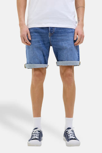 Middenblauwe denim jeansshort van JACK & JONES JEANS INTELLIGENCE, met opgerolde pijpen, gecombineerd met witte sokken en blauwe schoenen.
