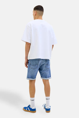 Lichtblauwe denim jeansshort van JACK & JONES, gezien van achteren met opgerolde pijpen en witte sokken met blauwe sneakers.