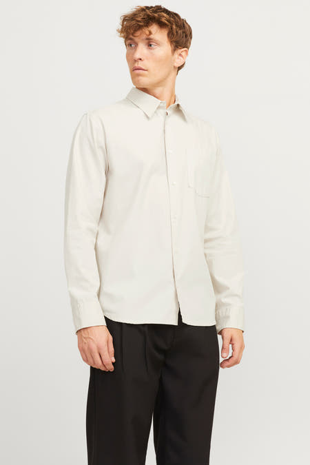 Ecru overhemd met lange mouwen van PREMIUM by JACK & JONES, met borstzak, gedragen met zwarte pantalon.
