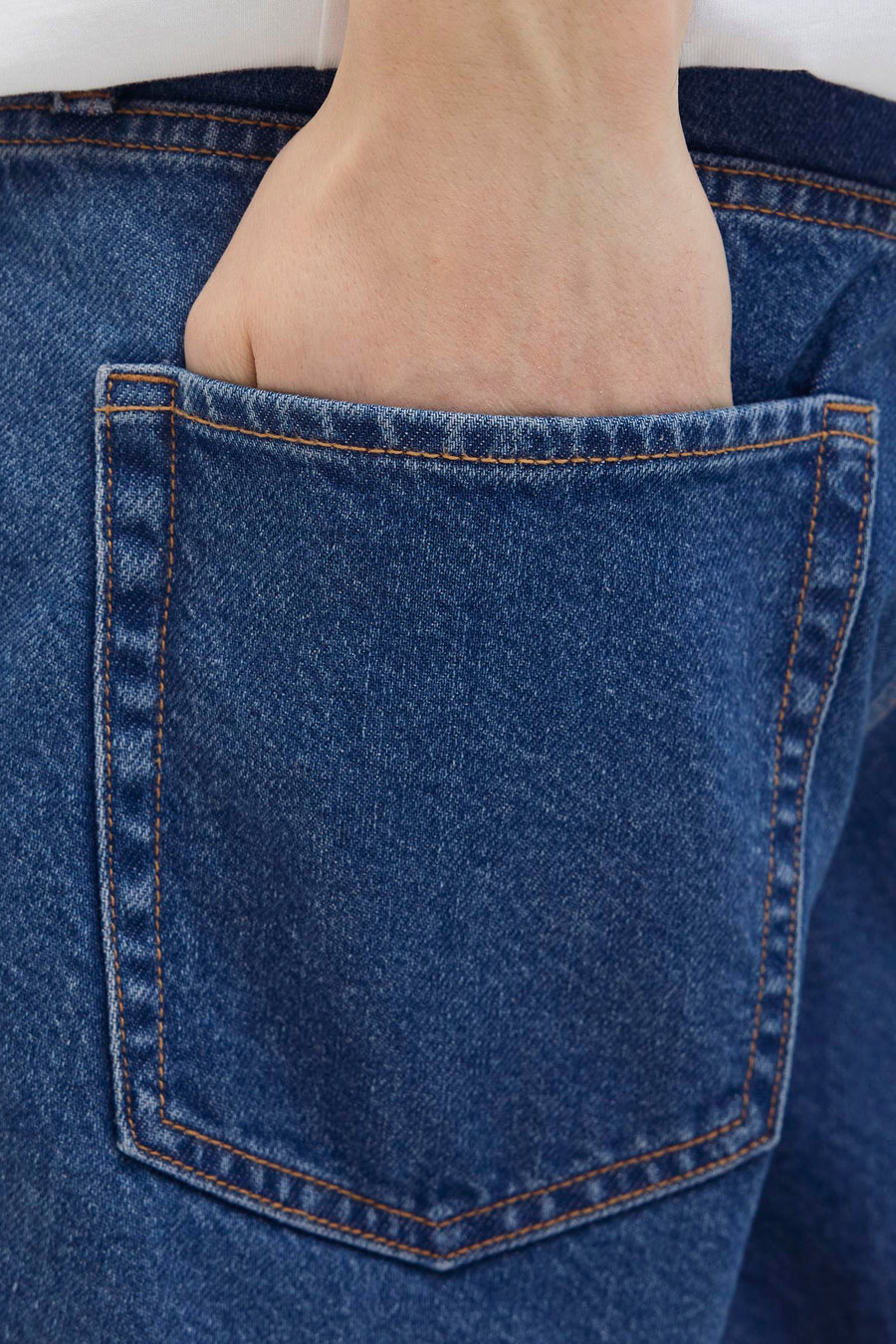 Short en jean denim bleu moyen de JJREBEL, main dans la poche arrière, gros plan.