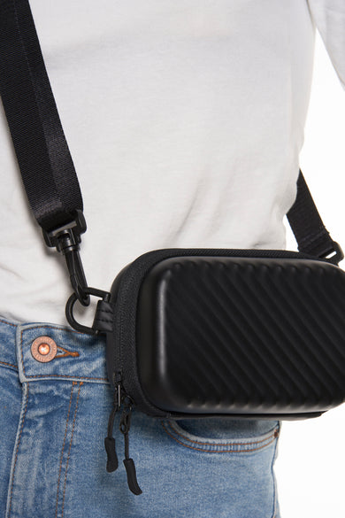 Zwarte schoudertas van ACCESSORIES BY JACK & JONES, met een diagonaal ribbelpatroon, gedragen op een wit T-shirt en blauwe jeans.

