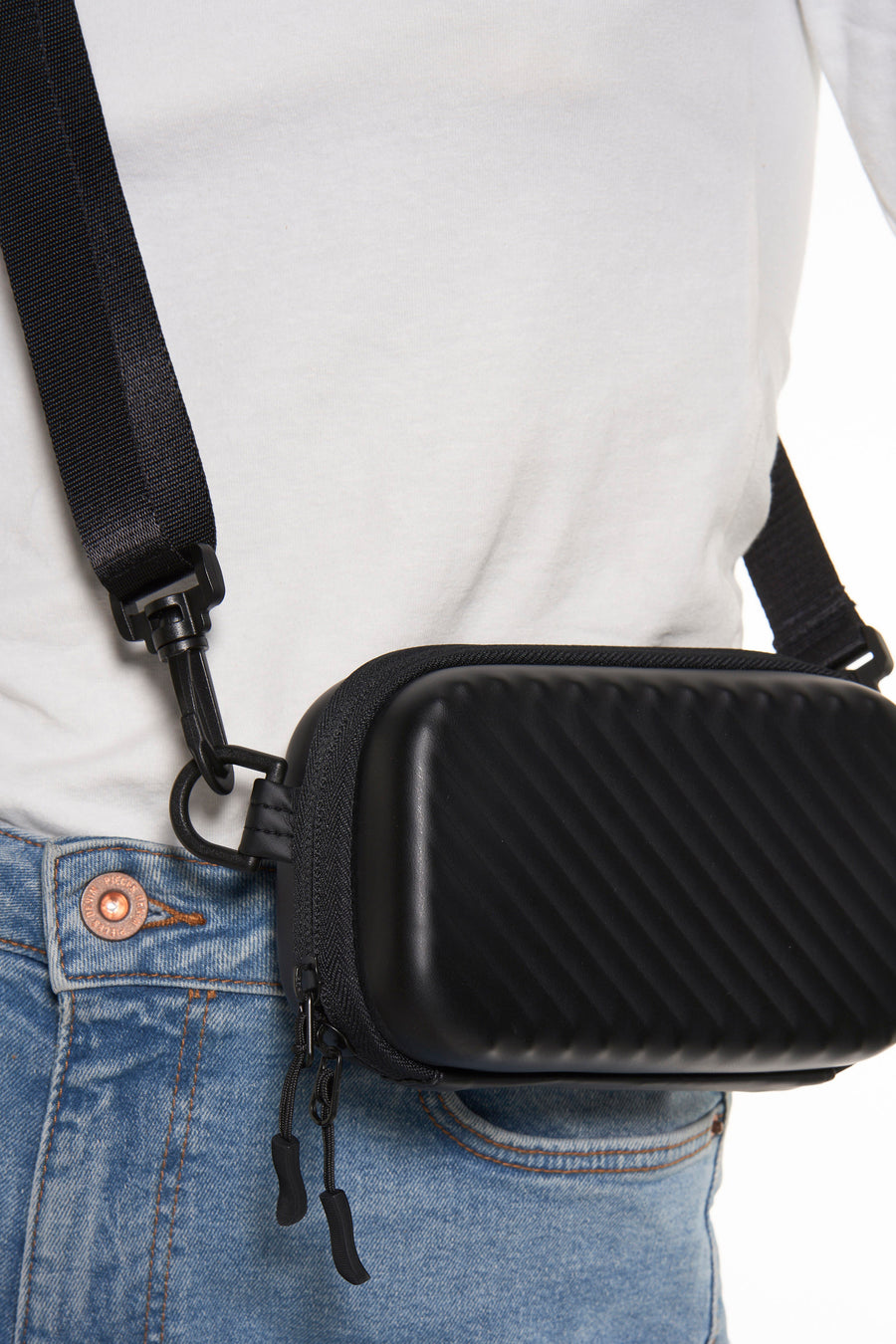 Zwarte schoudertas van ACCESSORIES BY JACK & JONES, met een diagonaal ribbelpatroon, gedragen op een wit T-shirt en blauwe jeans.
