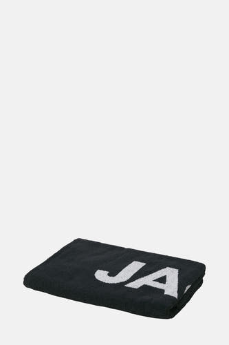 Zwarte strandkleding van ACCESSORIES BY JACK & JONES met witte "JA" print op een gevouwen handdoek.
