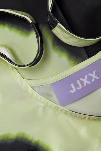 Groene blouse van JJXX, met een abstract zwart en groen patroon en een lila label.
