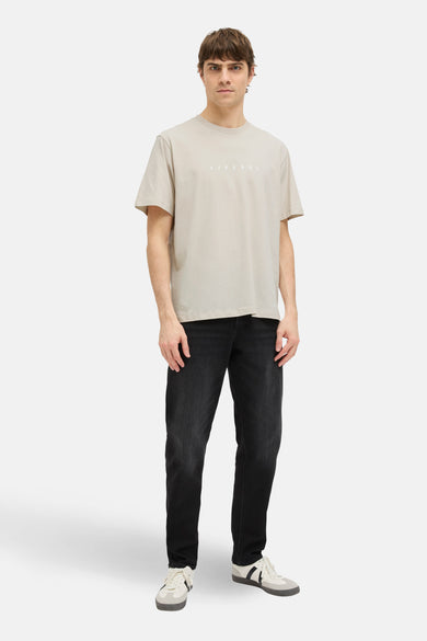 Beige T-shirt met korte mouwen van JJREBEL, met rechte pasvorm, gecombineerd met een donkere jeans en sportschoenen.