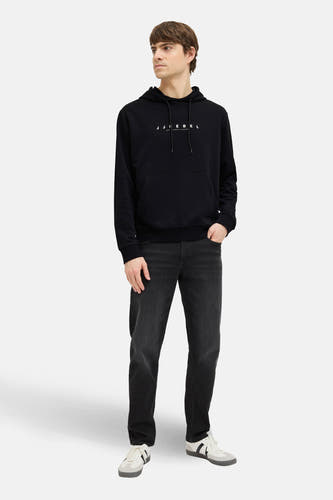 Zwarte sweater met kap van JJREBEL, gedragen met een donkere jeans en witte sneakers.