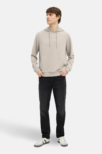 Beige sweater met capuchon van JJREBEL, met zwarte jeans en witte schoenen.