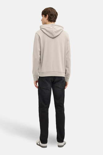Beige sweater met kap van JJREBEL, gezien van achteren, met donkere jeans en witte sneakers.
